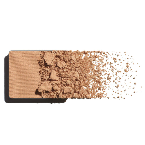 A peachy-beige eyeshadow refill, scattered on a white background